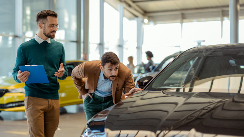 Car salesman showing a potential customer a car.