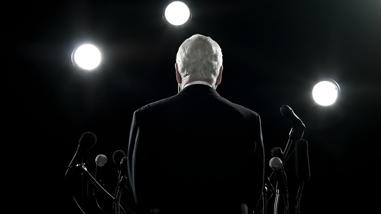 politician facing microphones