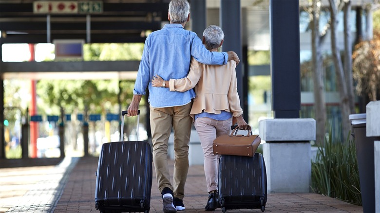 Senior couple walking with suitcases