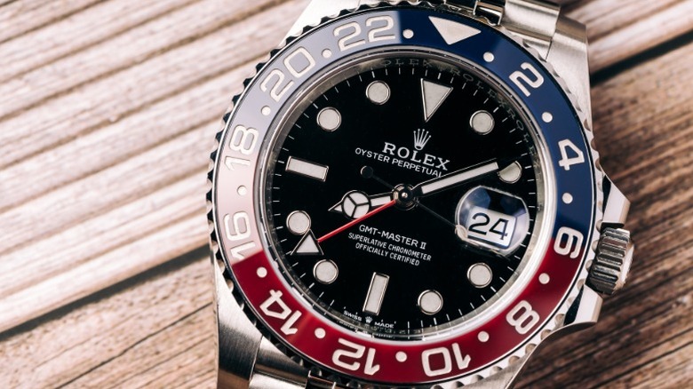 A GMT-Master II Rolex watch in Pepsi colors laying on a wood surface.