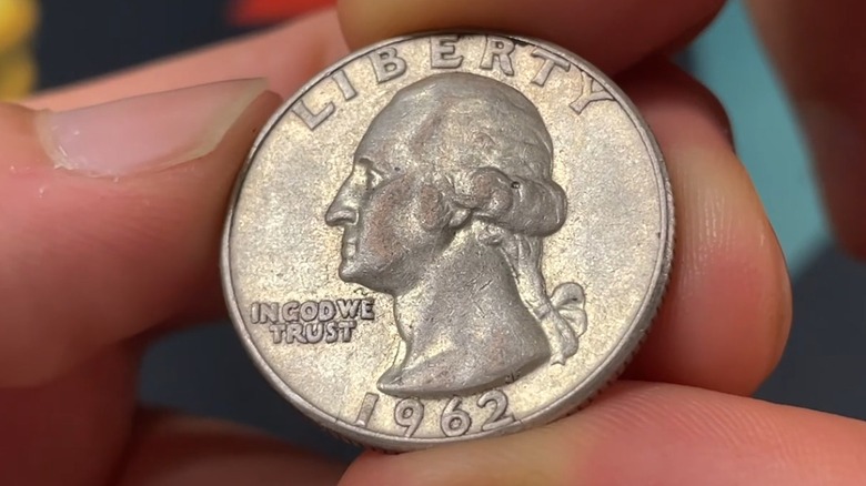 Close up of a 1962 quarter, held in a man's fingers