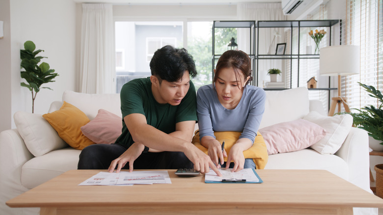 Young couple looks worriedly at papers