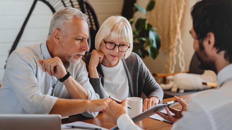 A senior couple discussing wills with a lawyer