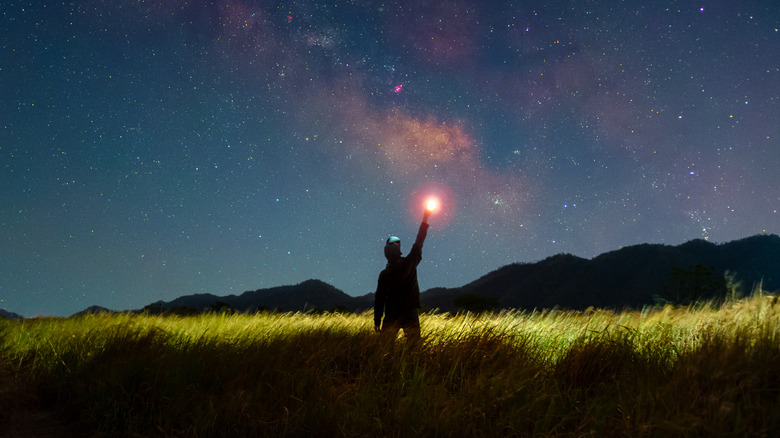 picture of man pointing to reddish bright star in night sky