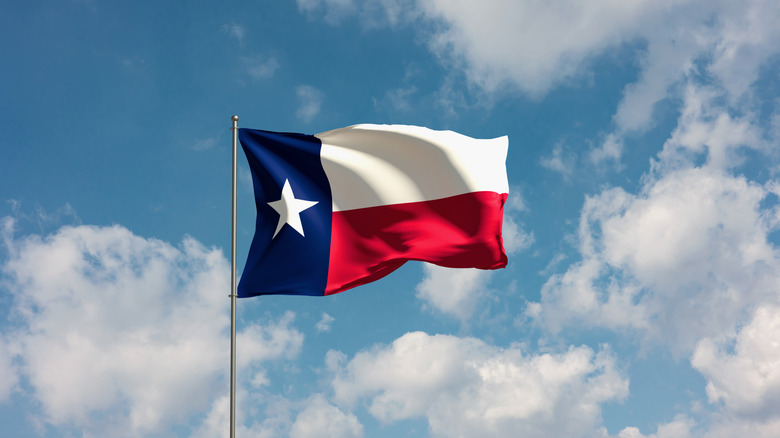 Texas State flag waving under a partially cloudy sky
