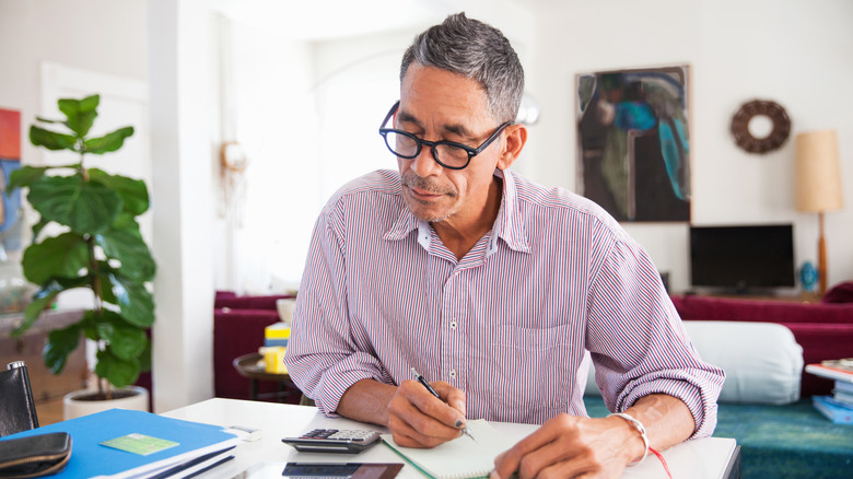 Man with glasses doing paperwork at table