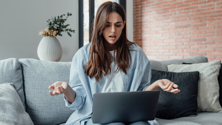 Surprised and frustrated young woman looking at a computer screen