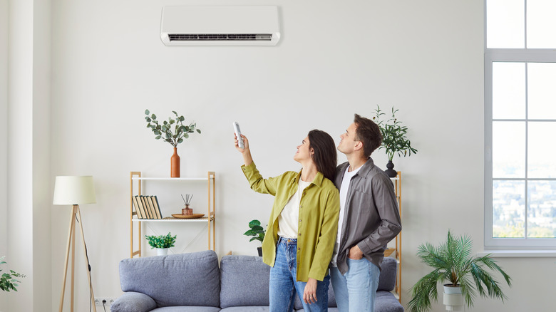 Couple turning on the wall mounted air conditioner at home