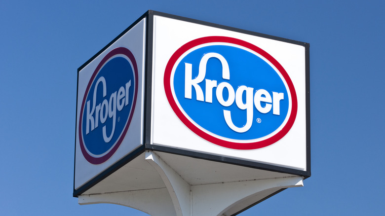 A four-sided Kroger grocery store sign sits atop a tall outdoor pole