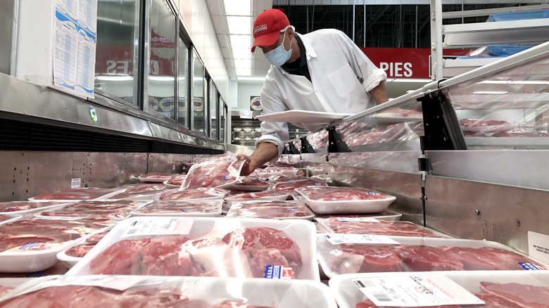 A Costco employee restocking meat fridge