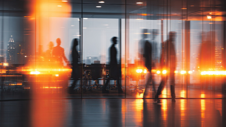 Silhouettes of people walking through an office in the evening