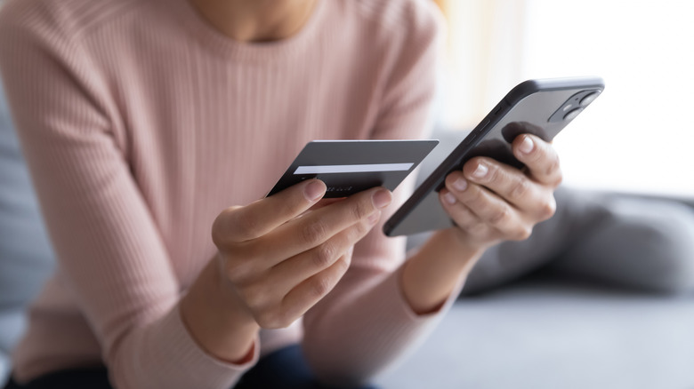 Woman examining card and phone