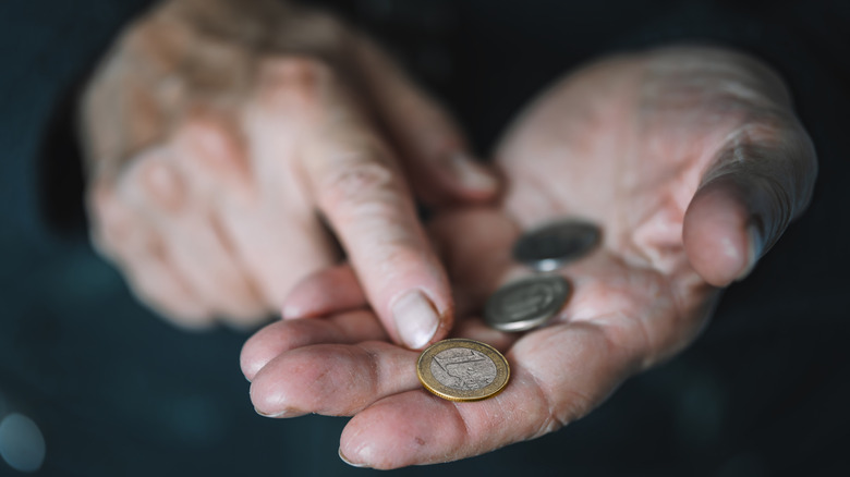 Finger pointing to old coins in hand