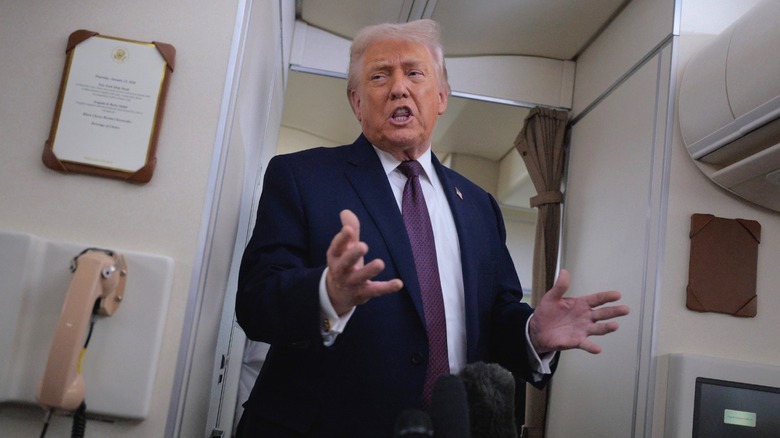 President Donald Trump gestures as he answers questions from the press on board Air Force One