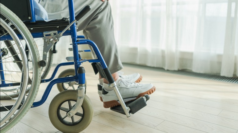 A person sitting in a blue wheelchair wearing sneakers.