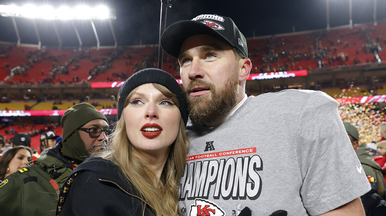 Taylor Swift and Travis Kelce posing together in stadium