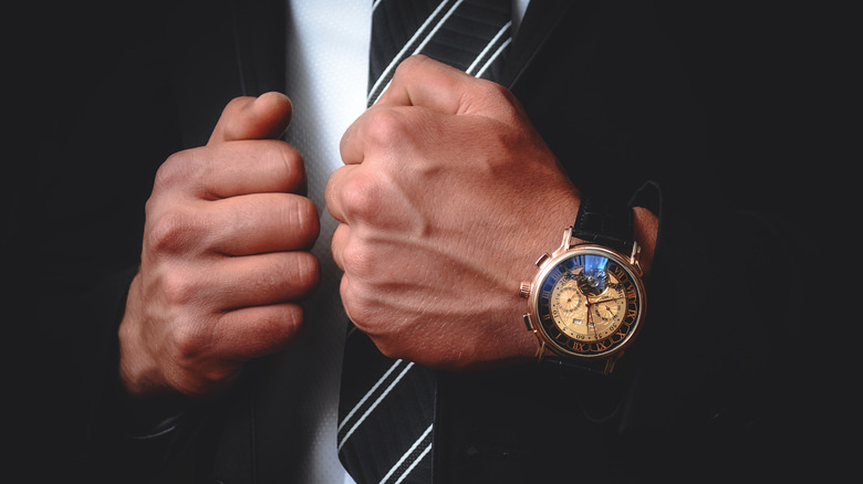 A man in a suit and tie wearing an expensive watch.