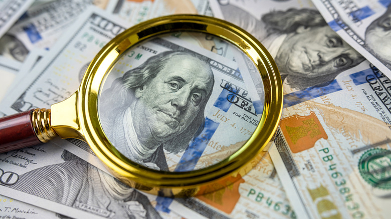 Hundred dollar bills under a magnifying glass