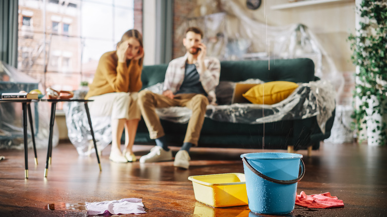 Stressed couple watching ceiling leak