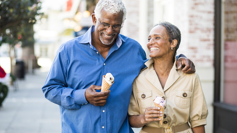 Elderly couple walking, eating treat