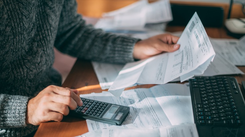Person holding bill, making calculations