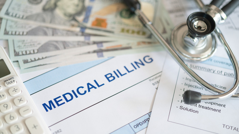 Stack of medical bills with stethoscope lying on top