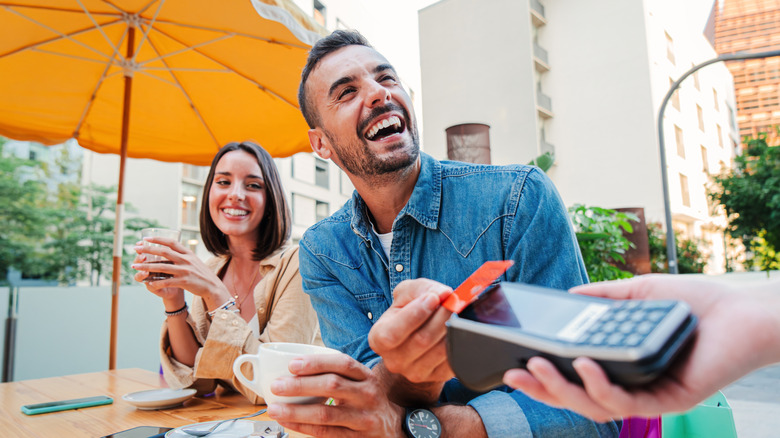 Couple paying for food while seating on outdoor patio