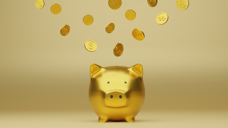 Gold coins raining down on a gold piggy bank.