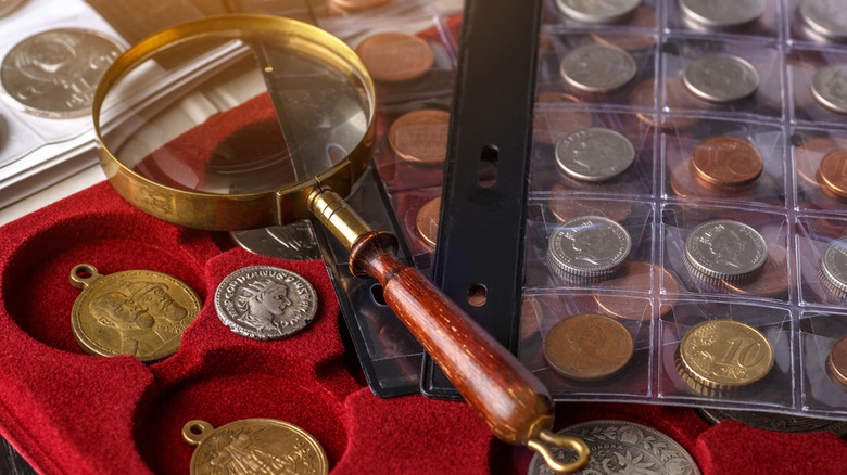 A magnifying glass with a variety of collectible coins.