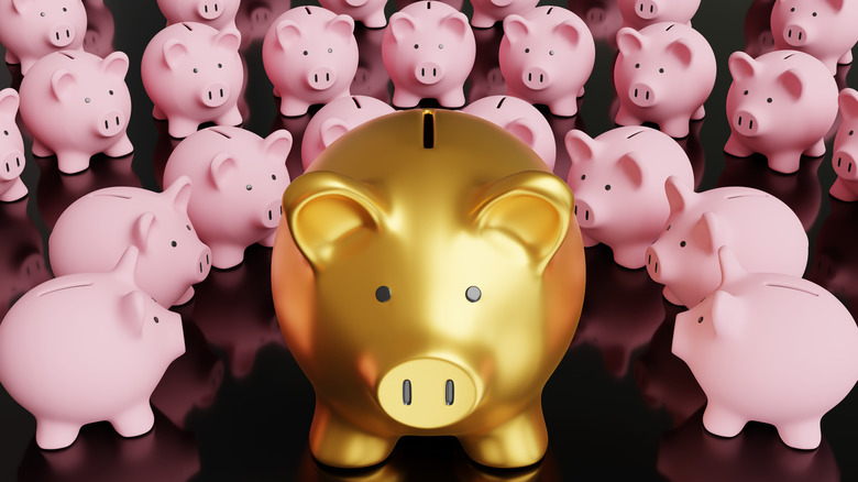 A gold piggy bank surrounded by pink piggy banks