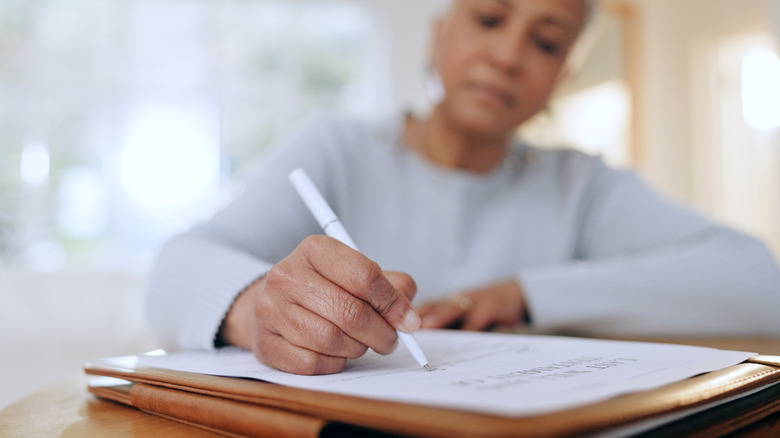 A mature woman writing on a piece of paper.