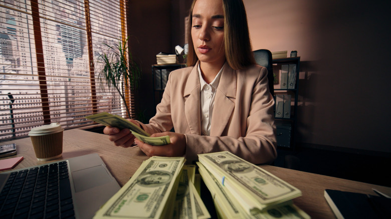 woman counting stacks of $100 bills