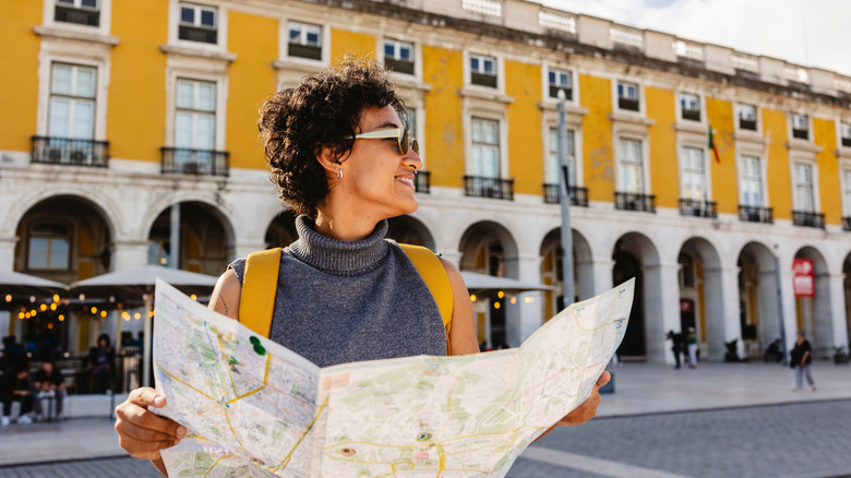 A tourist holding a map in front of a yellow building