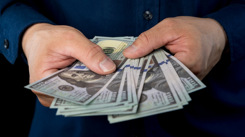 A person holding cash in their hands.