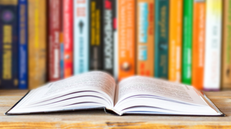 Open book on table in front of bookshelf