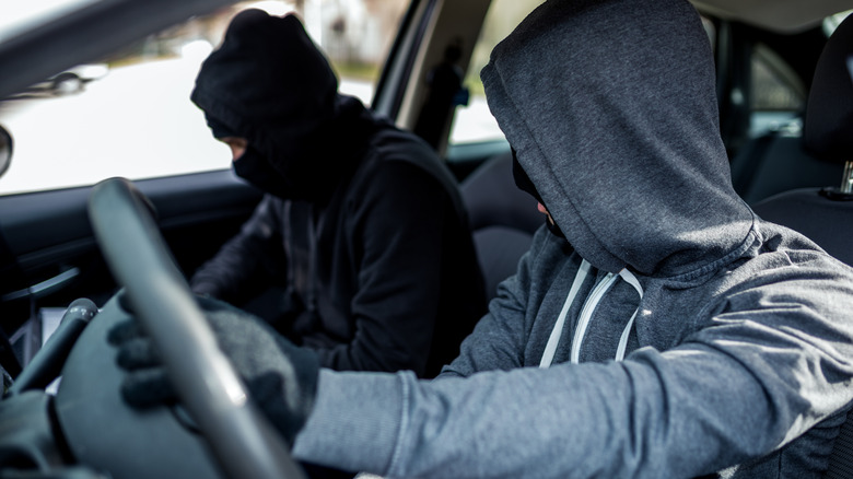 Two people hiding their faces while they steal a car