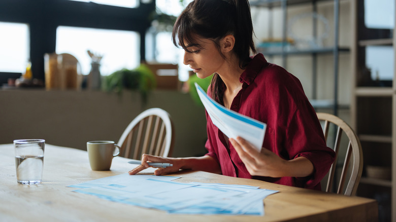Woman sitting at kitchen table going through financial paperwork
