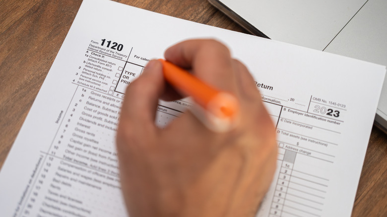 A close-up shot of a hand filling out tax forms