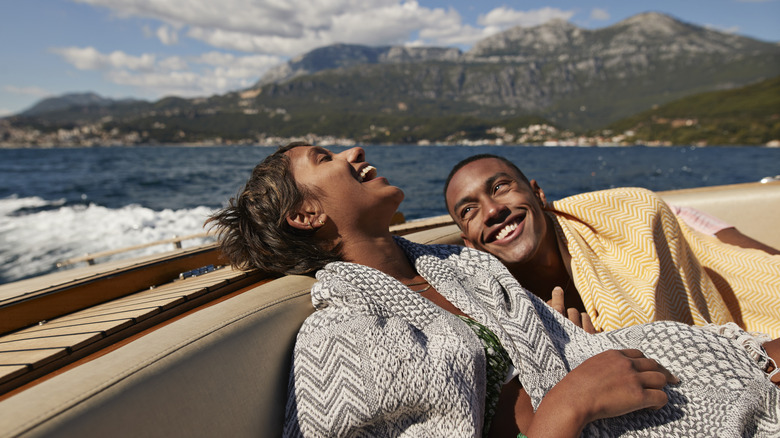 couple laughing in sun on speedboat