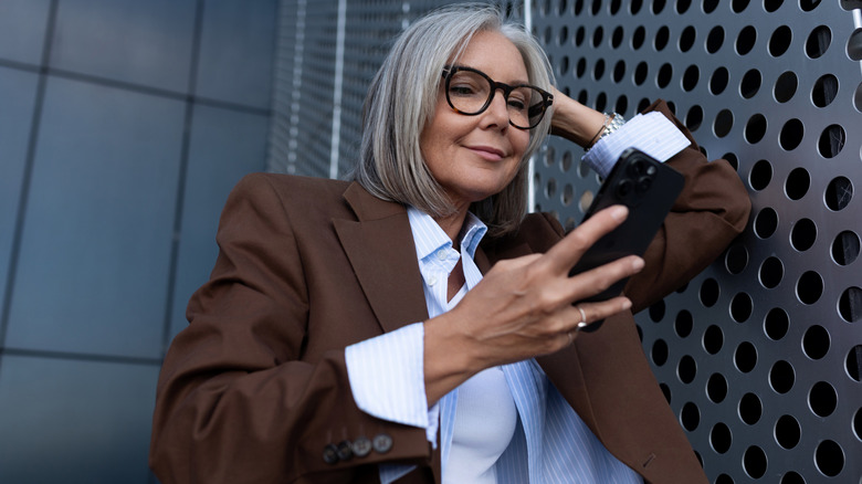 A stylish mature woman in professional clothing looking at her phone.