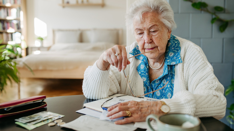 old lady looks over papers with money on the table