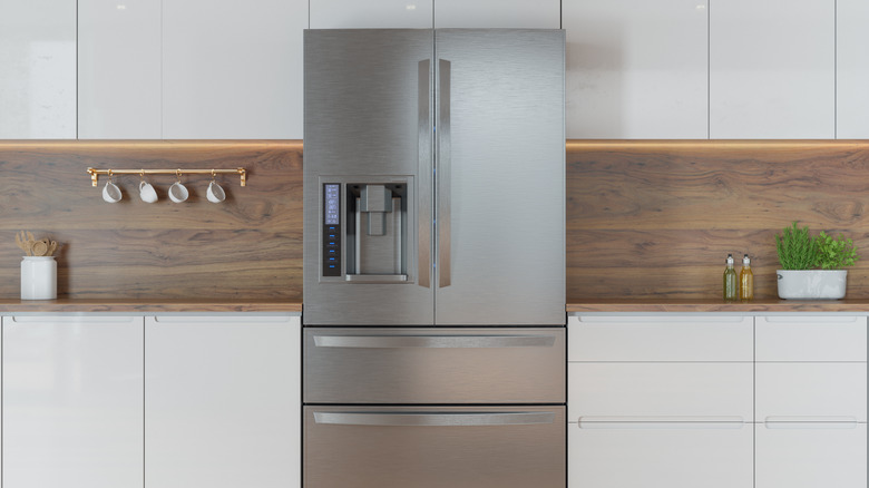 A modern kitchen with front view of refrigerator and white cabinets