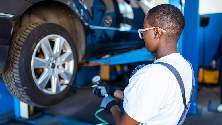 A female mechanic working on a tire in an auto shop.
