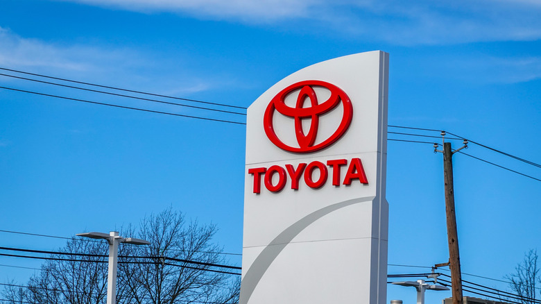 View of the a large Toyota car dealership road sign showing the company logo and Toyota name in red letter