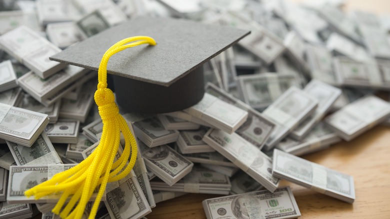 Graduation cap university or college degree on US dollars banknotes pile.