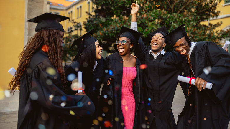 Group of cheerful black students celebrating their graduation day at the university campus