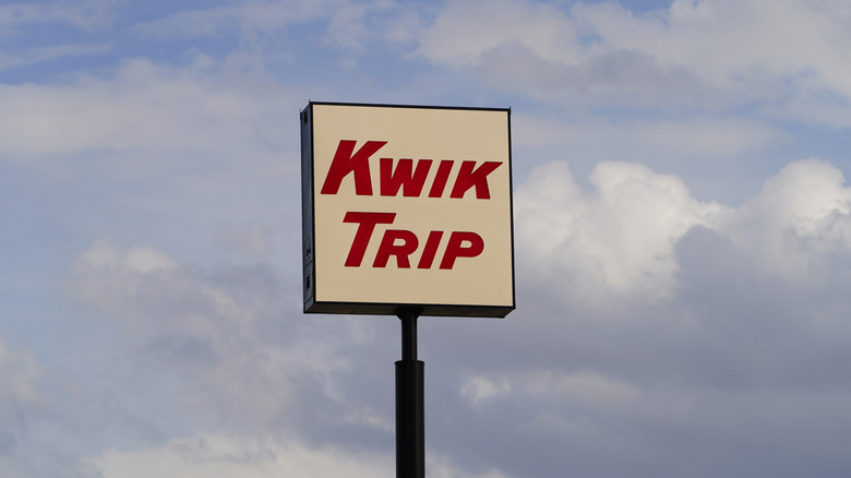 A tall Kwik Trip sign on a sunny, blue, cloudy day.