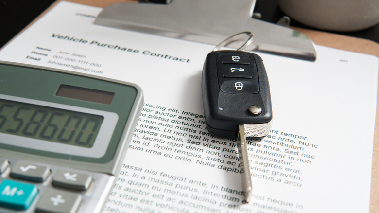 A car key laying on vehicle purchase paperwork.