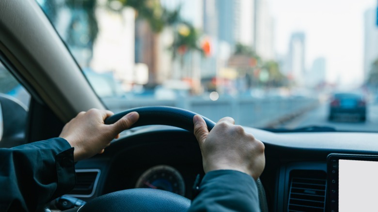 Close-up of hands on a car steering wheel.