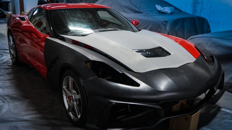 Damaged red and black Corvette (C7) parked in a closed garage